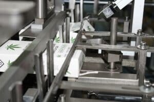 Assorted cannabis packaging: dropper bottle cartons, pre-roll drawer box, vape tin cases, and clear blister trays; child-resistant and odor-proof.